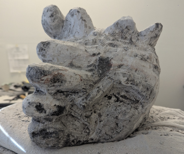 a sculpture depicting a head being held by a hand with brains oozing out of it